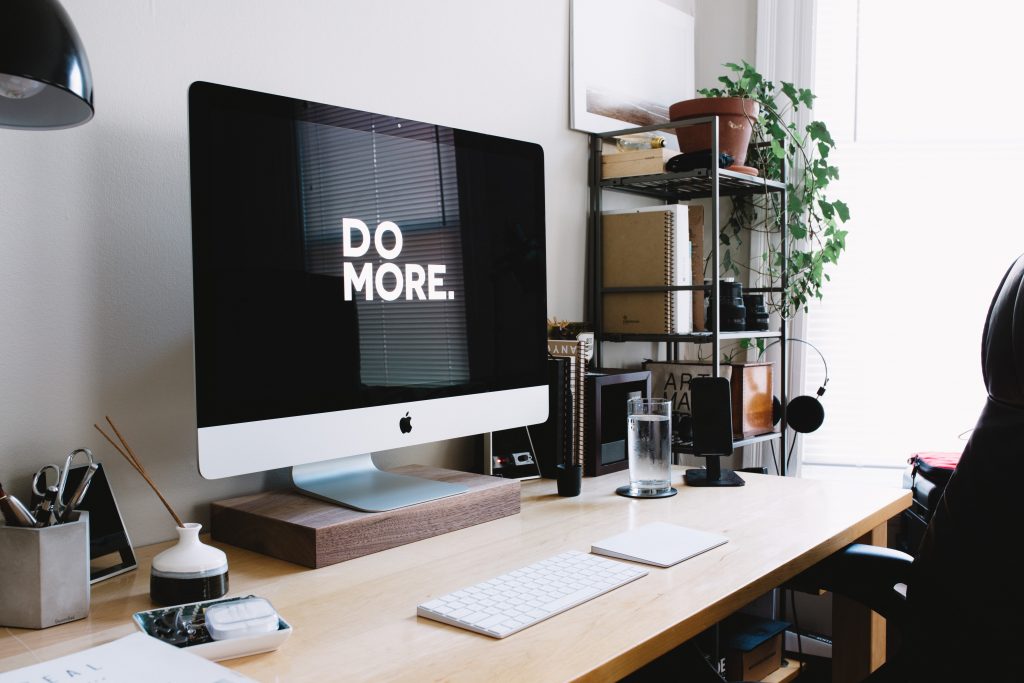 Computer on a desk with a screensaver that says "Do More"