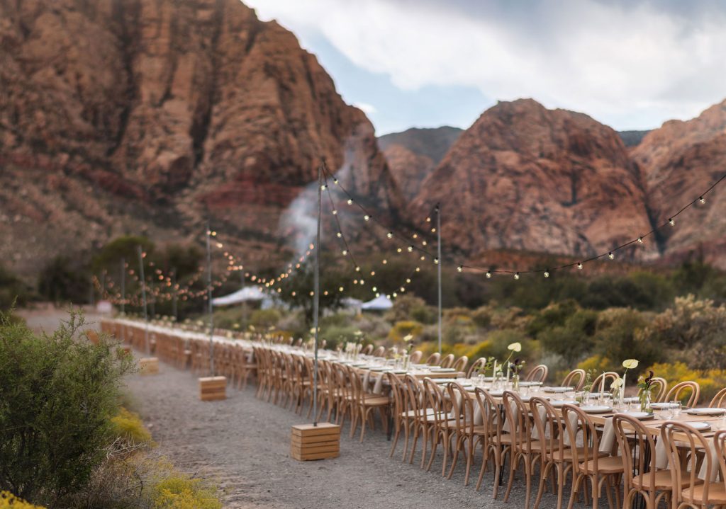 A communal table set up among the mountains of Las Vegas with bistro lights