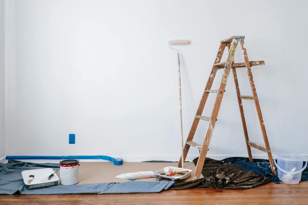 Brown wooden ladder next to painting materials in a home