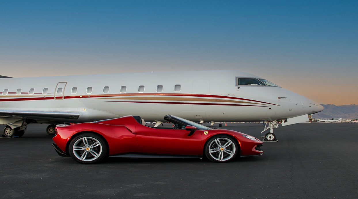 A red Ferrari parked next to a private jet on the tarmac