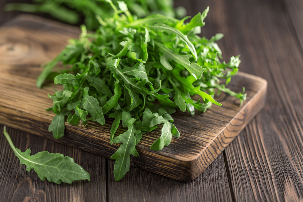 A bunch of arugula leaves on a cutting board