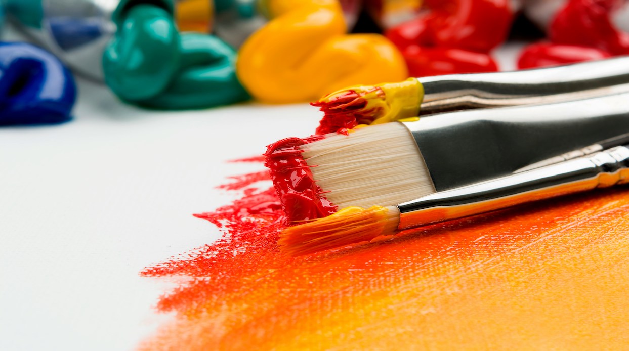 Paint brushes drenched in colorful paints