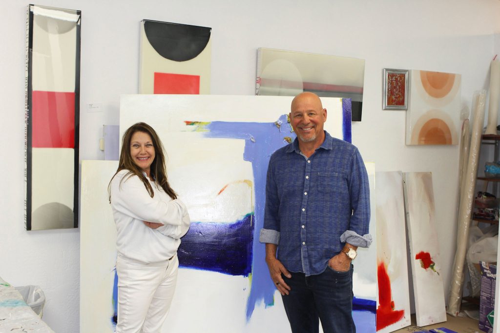 A man and woman in front of a painting