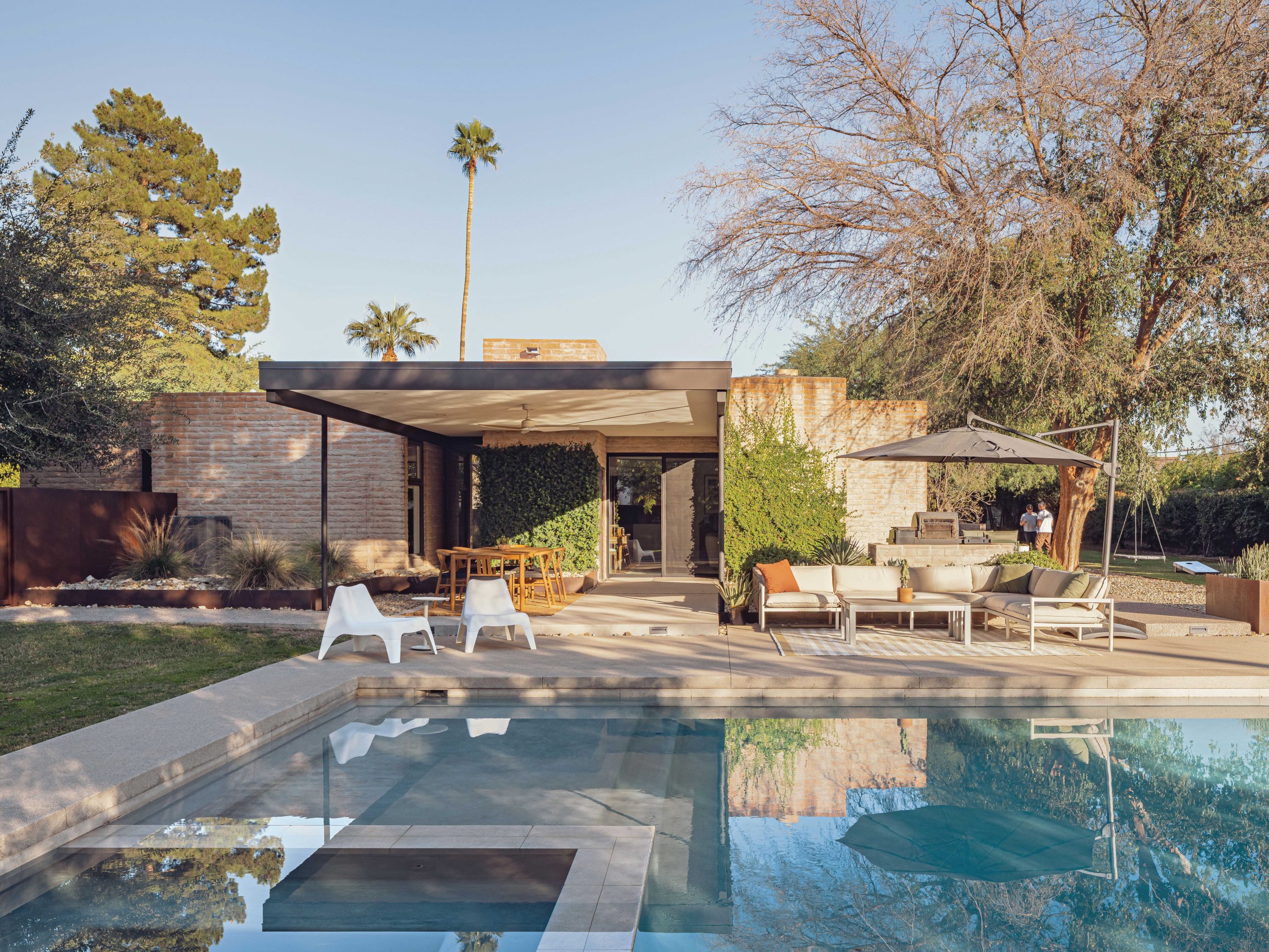 A new pool, patio and barbecue create an outdoor room, shaded by a cantilevered metal canopy.