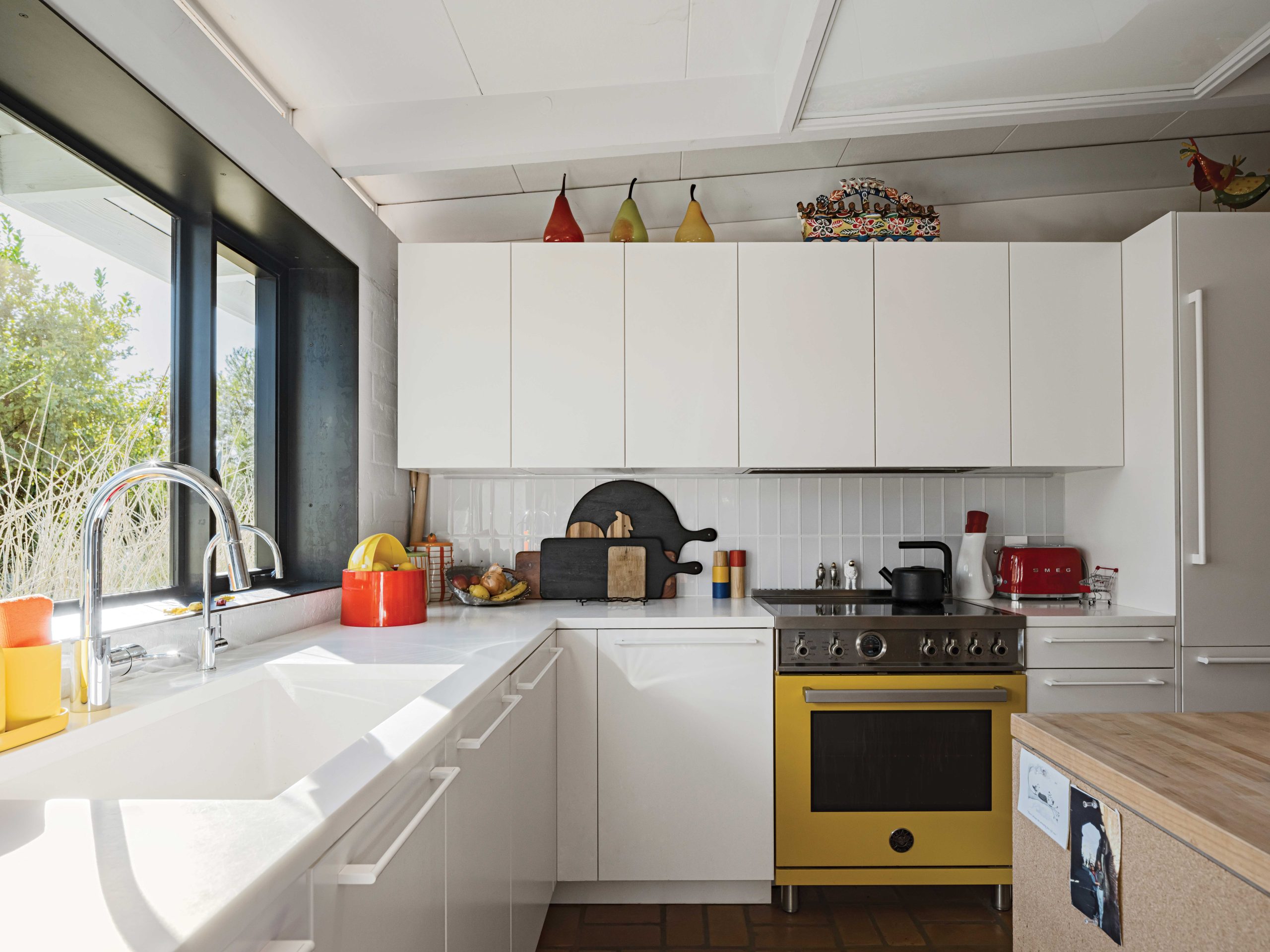 Burnette kept the kitchen’s original footprint, trading dated reddish-brown cabinets for sleek white versions, finished with a modern white counter and white tile backsplash. He enlarged the room’s window and added a deep steel frame. “I wanted to respect the genius of the original design,” he says. Helen, who loves color, insisted on adding a bright yellow range.