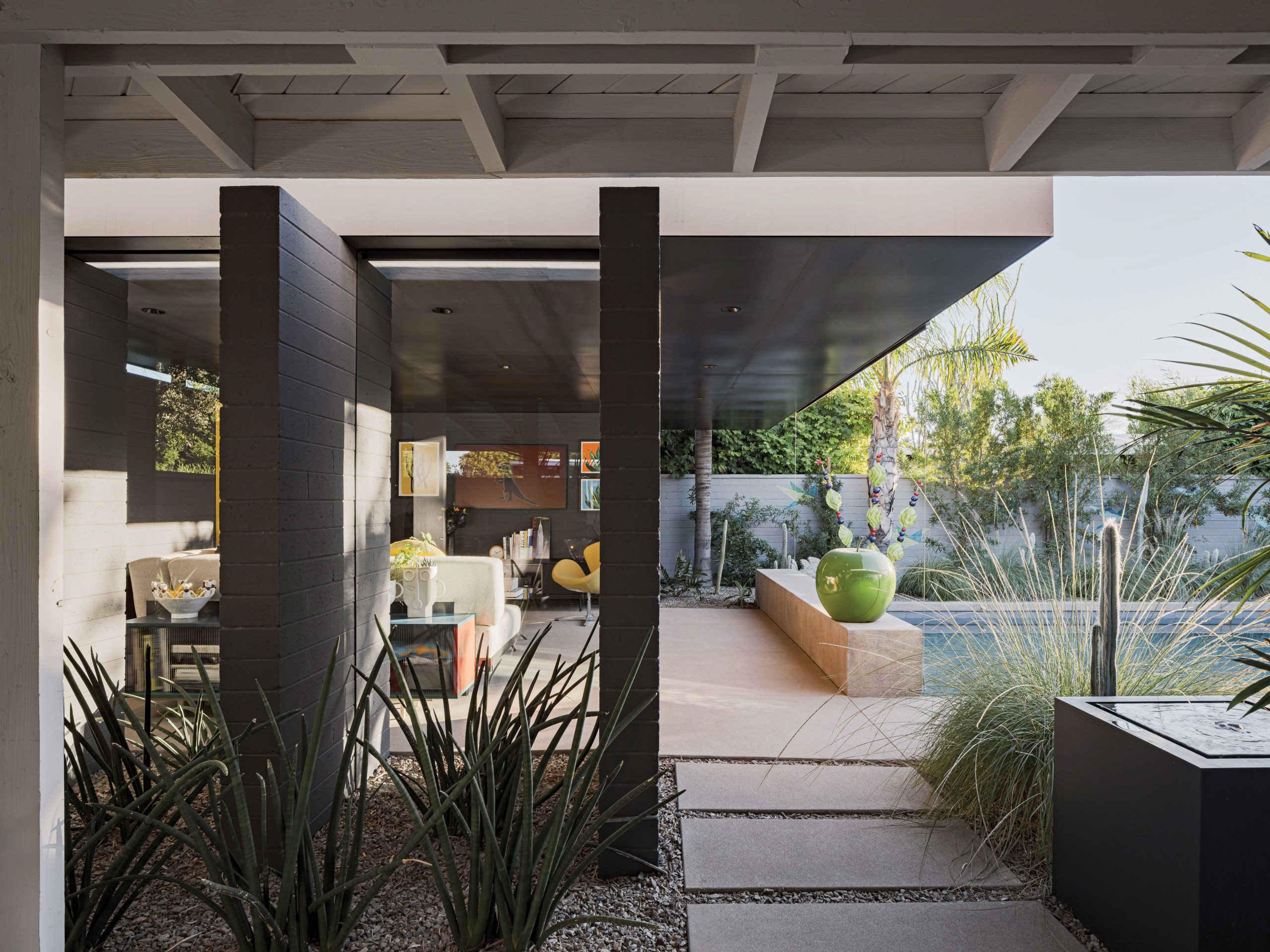 The west-facing glass wall of the casita slides open to offer unobstructed access to the pool and yard. A low bench-like divider wall serves as a barrier to the pool—“so you don’t accidentally walk into the water,” Burnette says—and offers additional seating. A sunshade can be pulled down from the steel roof and connect to the bench. Landscape architect Michele Shelor added native bunchgrasses, cacti and agaves for a lush garden look that’s drought-tolerant and easy to maintain.