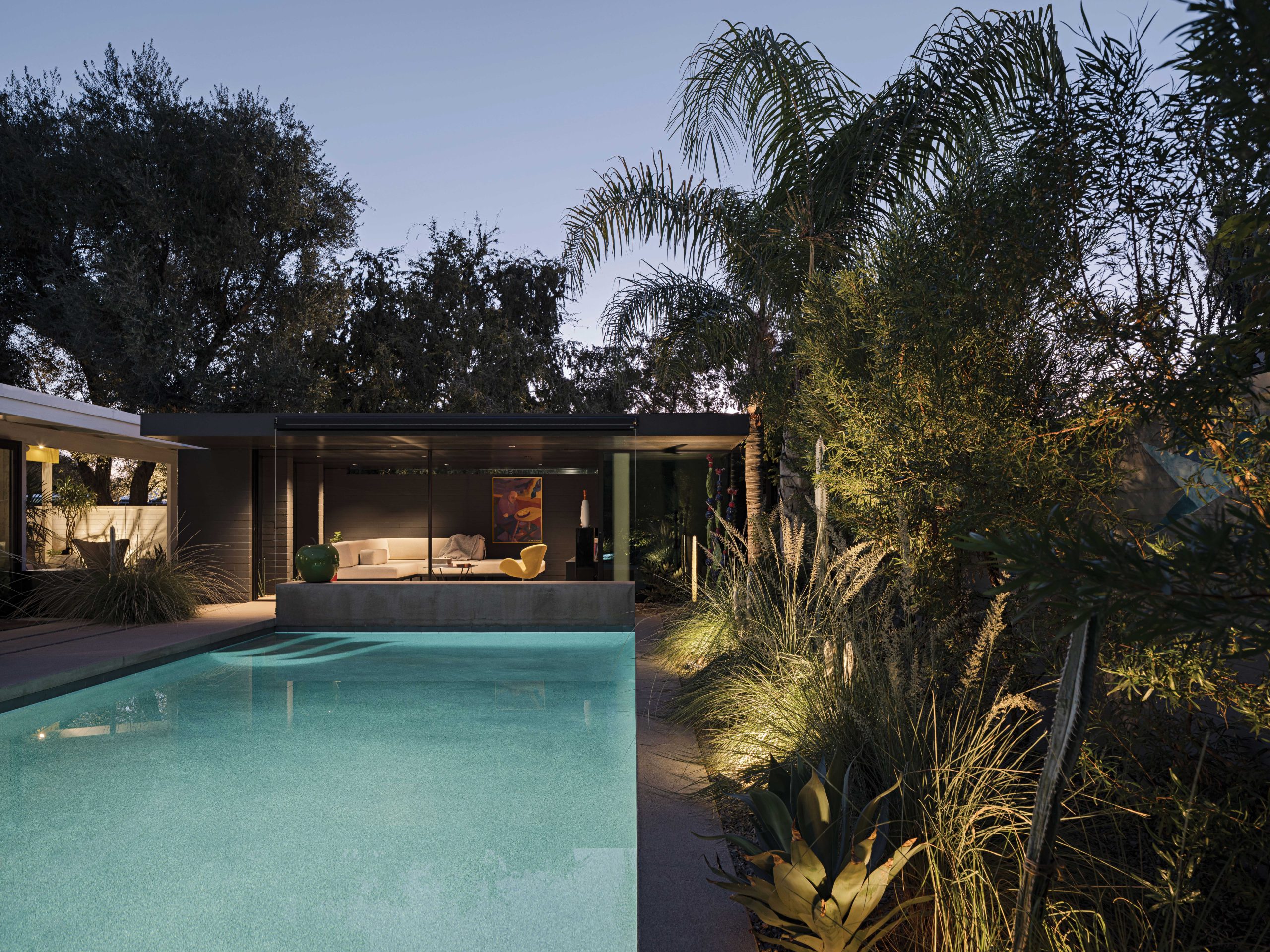 Burnette designed the casita to recede into the yard. “It’s very diminutive and quiet, acting kind of like a shadow,” he points out. Its low roofline is no taller than the outside edge of the gables of the main house, ensuring that it does not compete with Haver’s architecture. The large artwork behind the sofa was painted by a friend of the Winkels’ son.