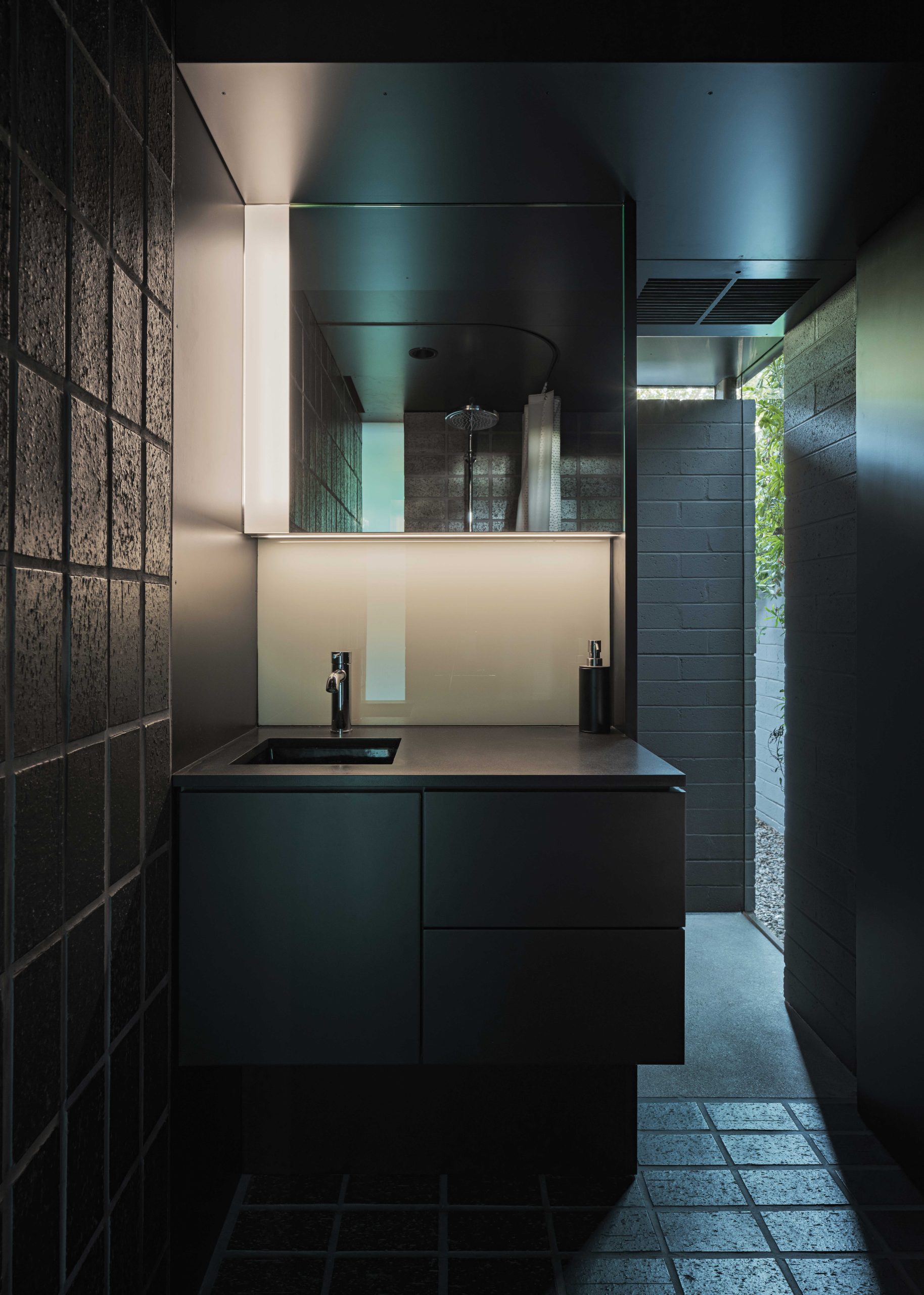 The casita’s small bathroom is cloaked in dark Endicott tile. The sink space serves both the bathroom and kitchenette, which is on the opposite side of the wall.