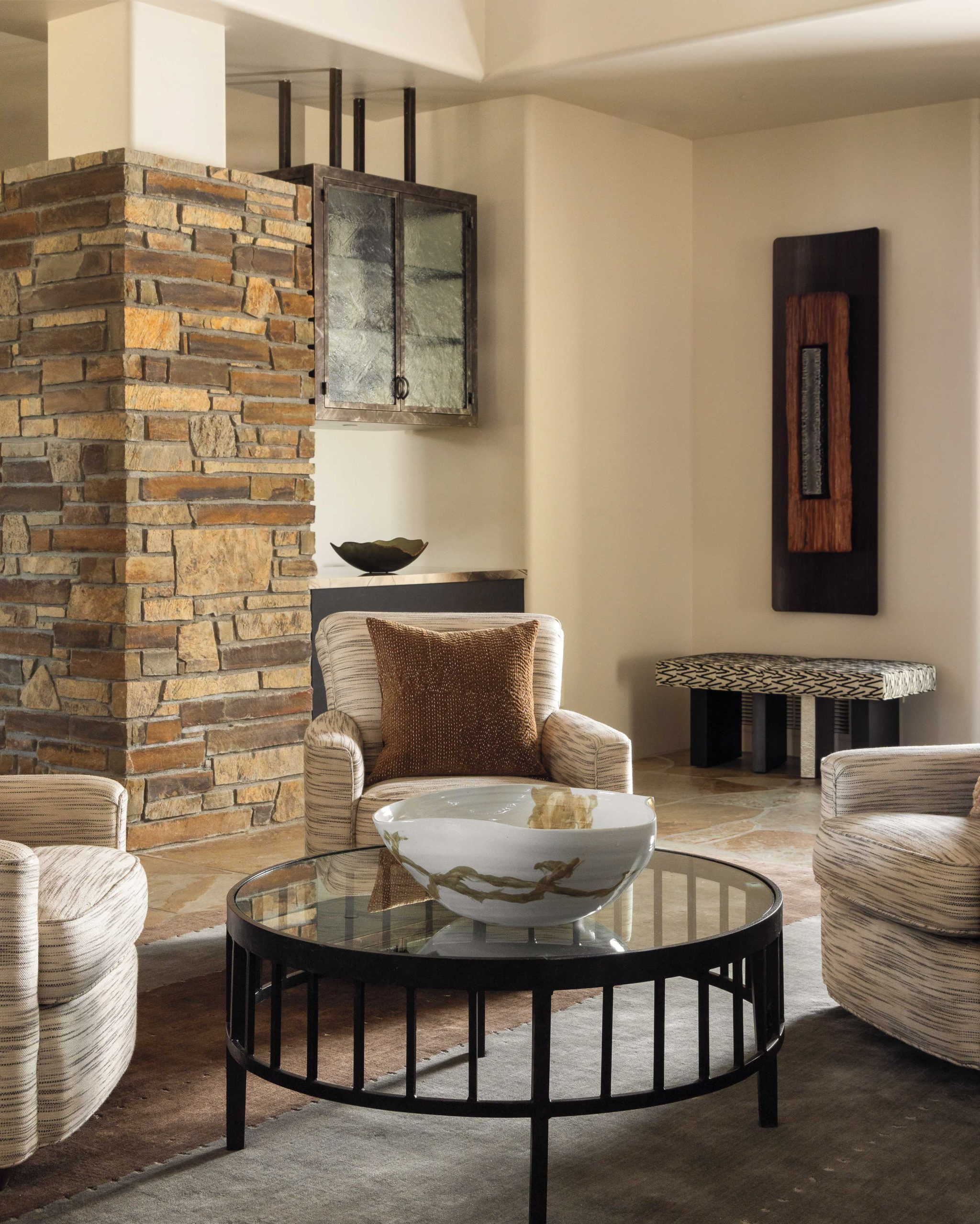 Interior designer Angelica Henry refreshed a home she first did in the early 2000s, focusing on brighter hues and artistic details. Keeping the original stone details, she designed new steel and art glass hanging cabinets for extra storage, and reupholstered the armchairs in a lighter fabric. A new bench underscores artwork by Cave Creek-based Carlos Page. “The flagstone flooring is classic,” says Henry, “and we saw no need to replace it.”