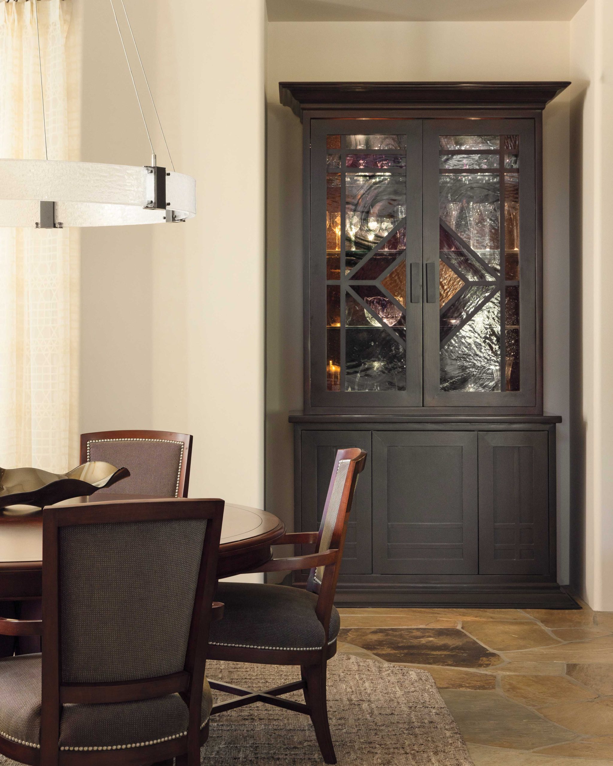 A new light fixture and area rug update the dining room, where the original custom cabinet displays tabletop treasures.