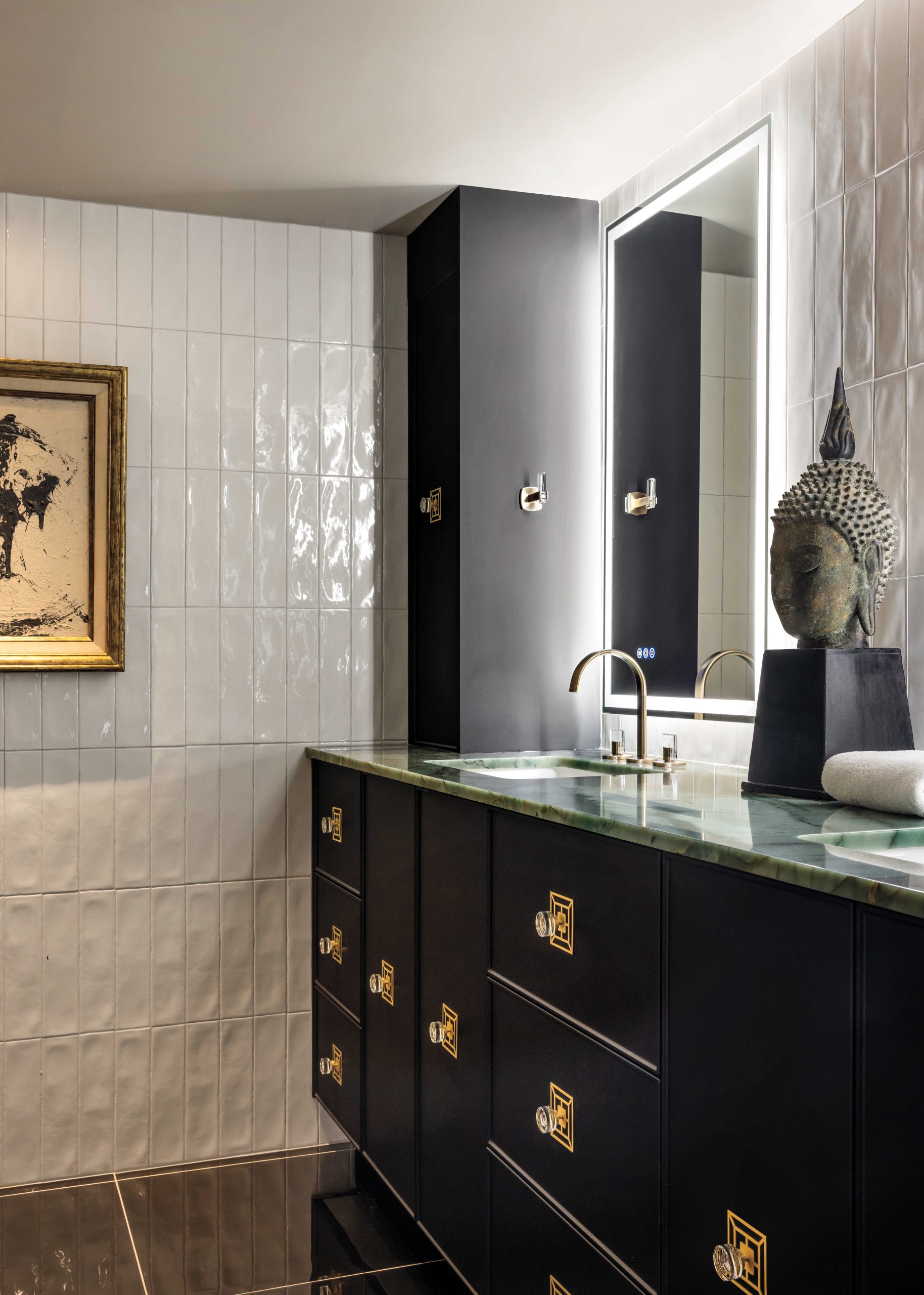 Soldiered tiles in the primary bathroom are a respectful homage to The Olympus’s original builder, Robert C. Crabb, owner of the Monarch Tile company. Storage towers at either end of the vanity conceal essentials. An antique Thai Buddha head stands sentry, accenting the green and turquoise countertops. “Why not turn your bathroom into an art experience?” McIntyre muses.