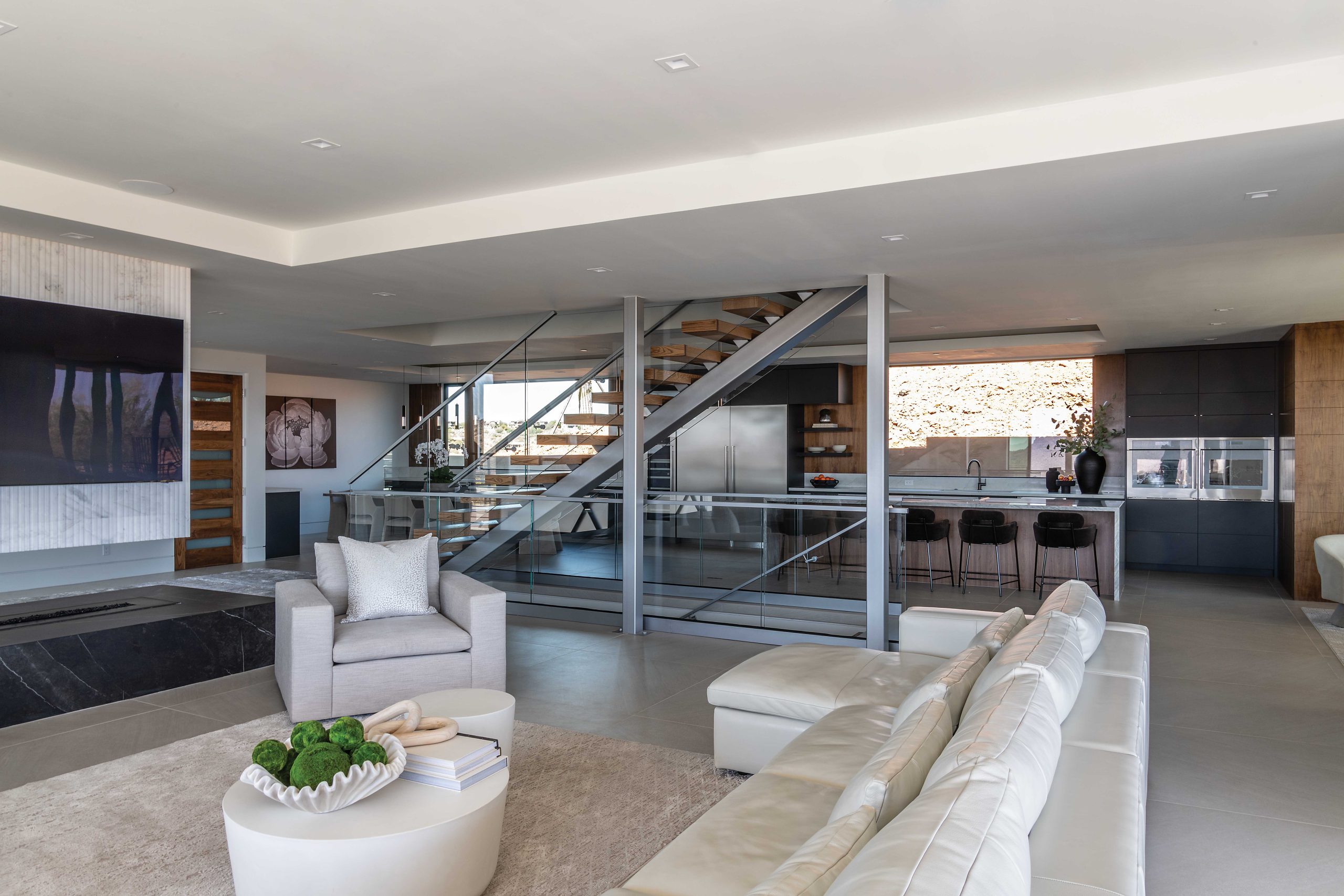 The fireplace was originally located between the two support columns next to the floating staircase. Marek suggested repositioning it near the entry and giving it three sides, which freed up views of the kitchen and dining room—and gives it a wow factor. “You experience the fireplace from the entry and from all angles of the home. Relocating it lets the staircase speak,” she says. “We were able to incorporate the columns in a contemporary way, making them an accent rather than a focal point.”