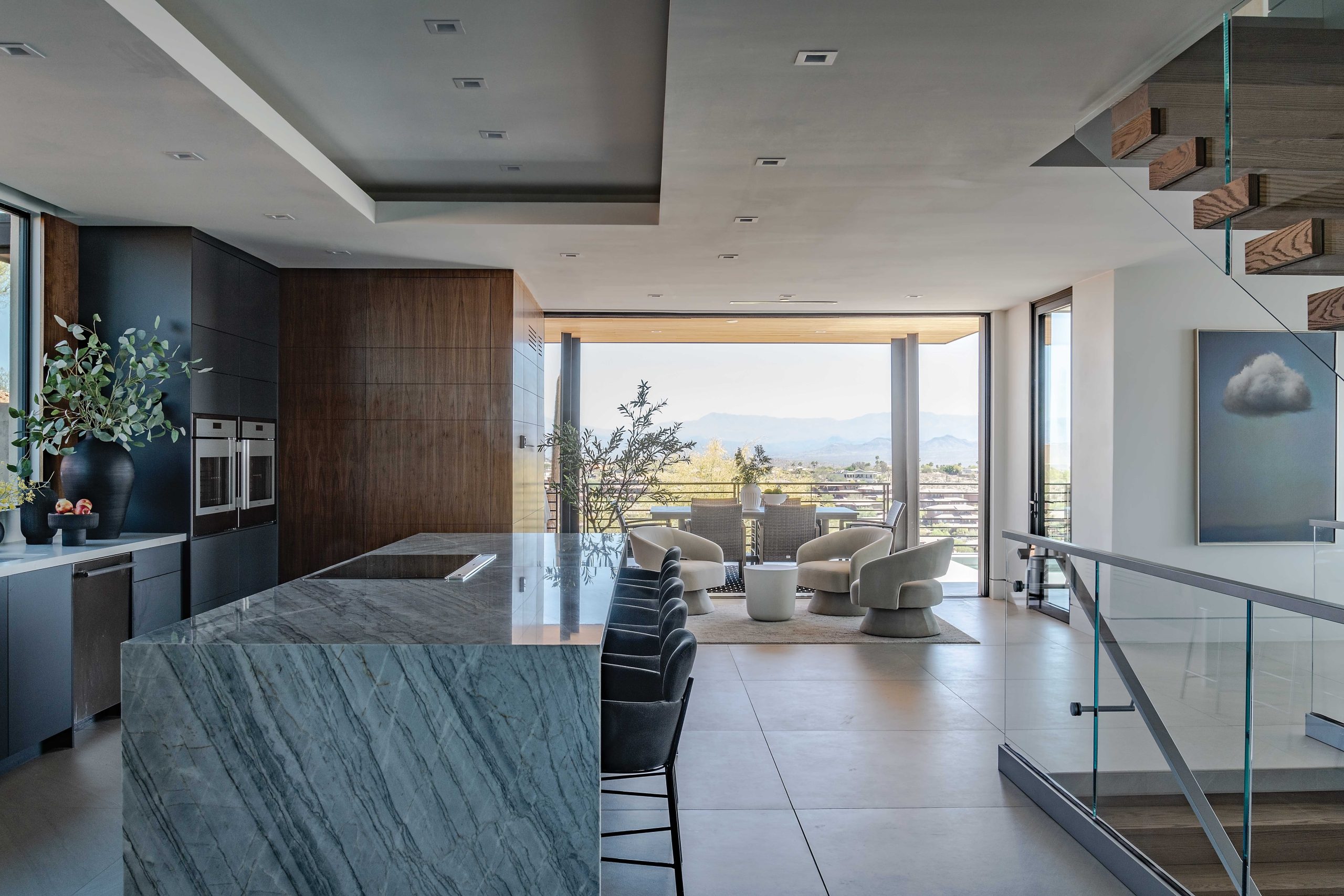 A lit, raised soffit runs the length of the dining table and kitchen island. “It creates a visual illusion of the length of the spaces and also joins them,” Marek says. Adjacent to the ovens, a hidden pantry provides additional storage.
