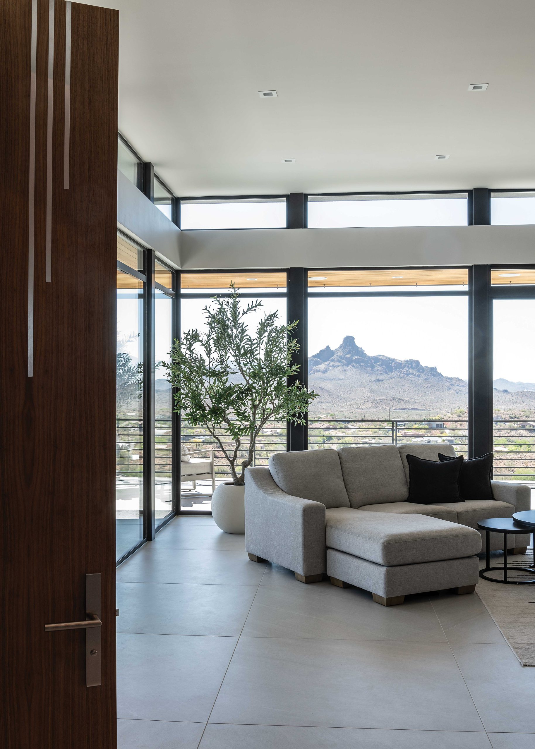 This glimpse of the primary bedroom shows views of Red Mountain. Large-format cream floor tile was incorporated throughout the home. “Tile is a light accent that makes everything else pop off the walls,” observes Marek. “Your eye is not distracted by a grid of grout lines.” Solid walnut interior doors are inlaid with a stainless-steel motif, providing a subtle visual note.